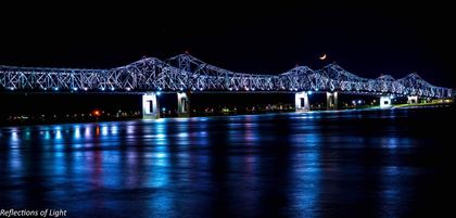 Illuminated bridge reflected in dark blue water at night