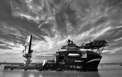 Black-and-white offshore vessel beneath dramatic clouds