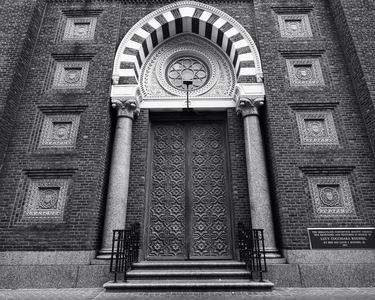 Black-and-white Romanesque church doorway framed by patterned brick