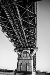 Black-and-white architectural view beneath a steel bridge